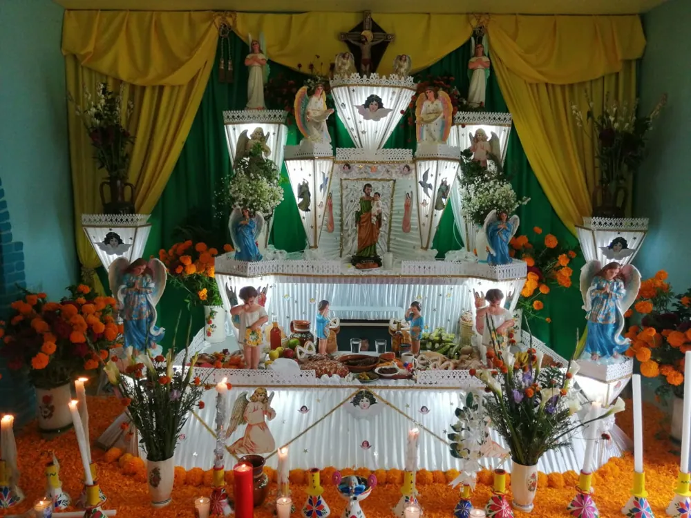 Ofrendas de Día de Muertos con cempasúchil naranja, calaveras de azúcar de colores y papel picado morado y rosa