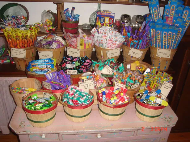 Mesa de dulces de baby shower con frascos de golosinas en tonos pastel, cupcakes y letrero