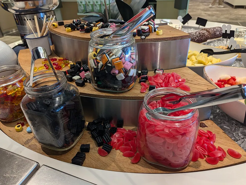 Mesas de dulces de distintos colores y estilos, con frascos, charolas y letreros, montadas en fiestas y en tiendas
