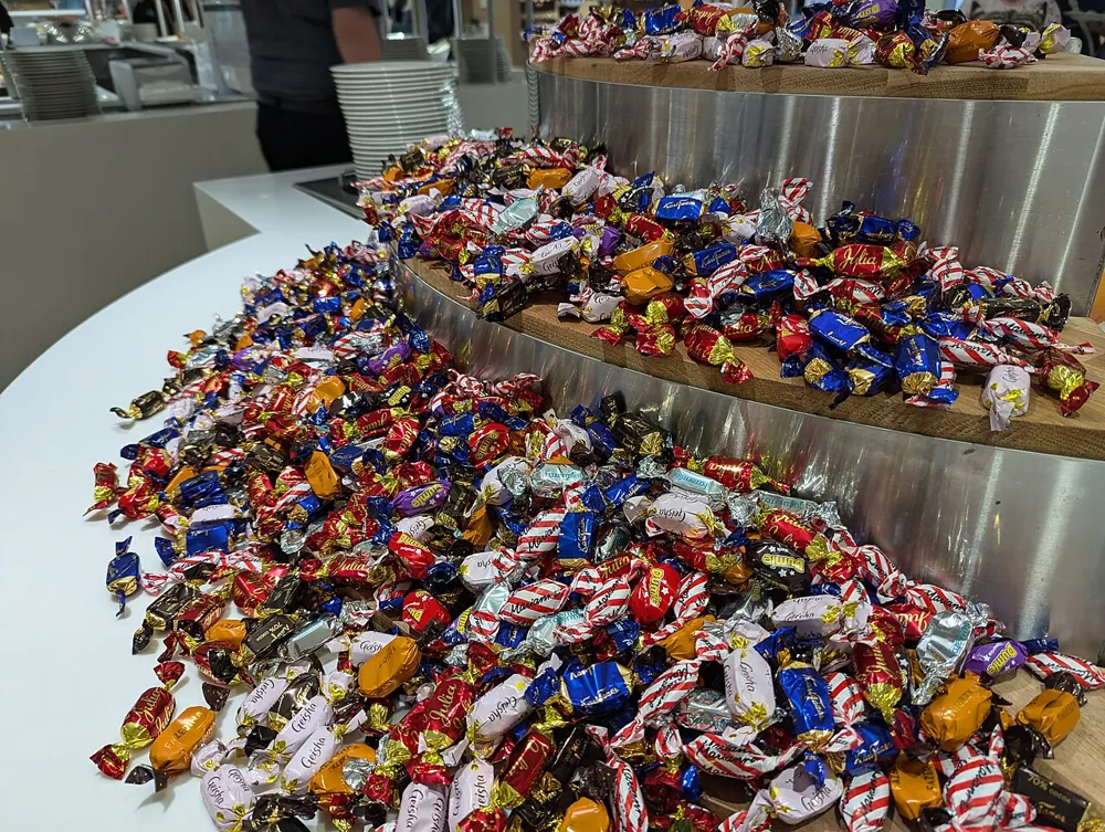 Mesas de dulces de distintos colores y estilos, con frascos, charolas y letreros, montadas en fiestas y en tiendas
